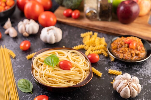 Spaghetti in einem grauen Teller mit Tomaten und Basilikum anbraten