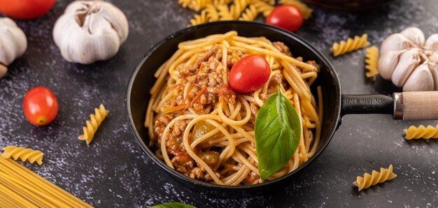 Spaghetti in einer Pfanne mit Tomaten und Basilikum gebraten