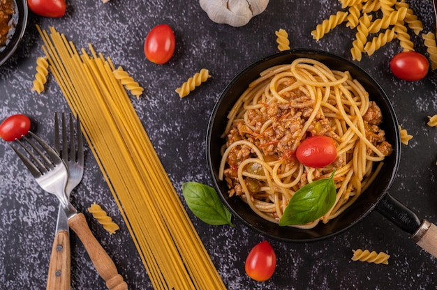 Spaghetti in einer Pfanne mit Tomaten und Basilikum gebraten