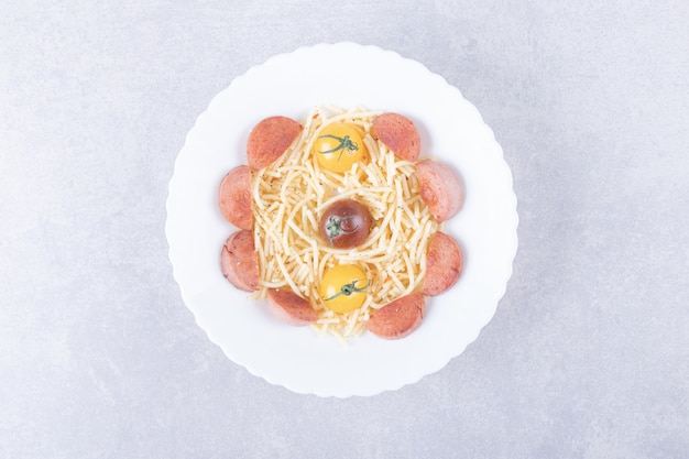 Spaghetti mit Bratwürsten und Tomaten in weißer Schüssel.