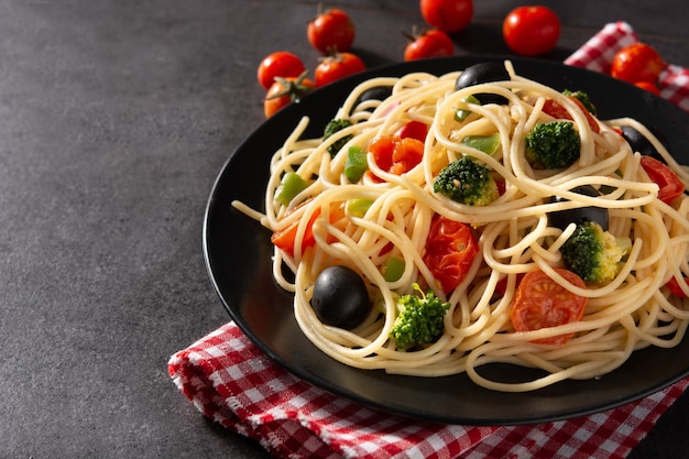 Spaghetti mit Gemüsebroccolitomatoespeppers auf schwarzem Schieferhintergrund