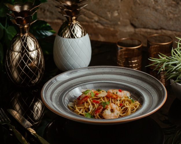 Spaghetti mit Meeresfrüchten und frischem Gemüse gekocht und in einer grauen Granitplatte serviert