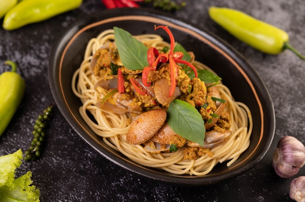 Spaghetti mit Muscheln in einem schwarzen Teller mit Chilis Frischer Knoblauch und Pfeffer.