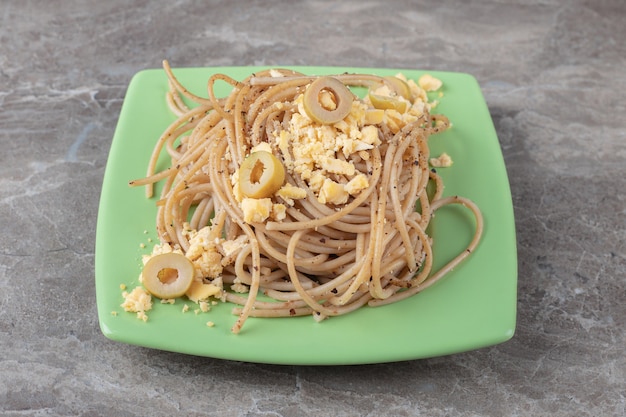 Spaghetti mit Spiegeleiern auf grüner Platte.