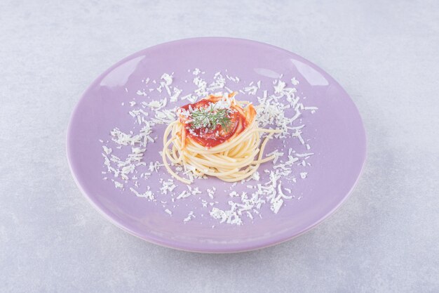 Spaghetti mit Tomatennudeln auf lila Teller.