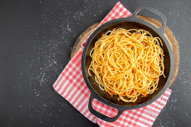 Spaghetti-Pfanne mit Draufsicht auf Holzbrett auf dunklem Hintergrund