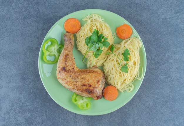 Spaghetti und gegrilltes Bein auf grüner Platte.