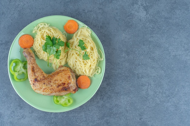 Spaghetti und gegrilltes Bein auf grüner Platte.