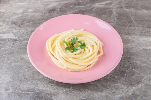 Spaghetti und Grüns auf dem Teller, auf dem Marmor.