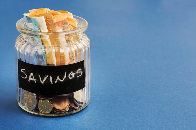 Sparen Flasche mit Euro-Banknoten und-Münzen auf blauem Hintergrund