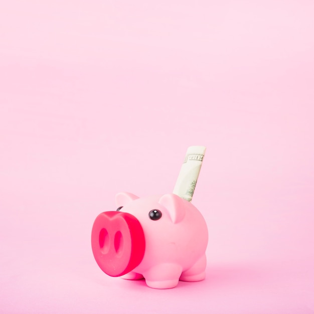 Sparschwein mit Geld auf rosa Hintergrund