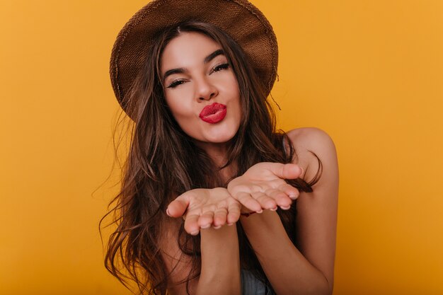 Spektakulär gebräuntes Mädchen mit hellem Make-up, das nach dem Fotoshooting Luftküsse sendet