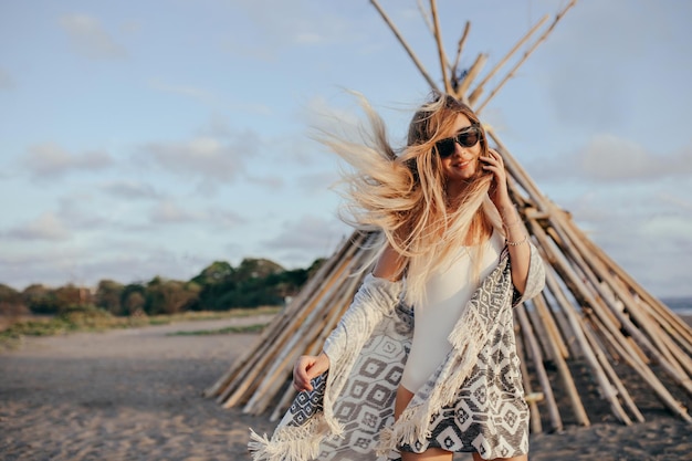 Spektakuläre kaukasische Dame mit langen Haaren, die an windigen Tagen am Strand posiert Außenaufnahme eines wunderbaren weiblichen Modells, das das Sommerwochenende in der Nähe des Meeres genießt