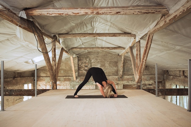 Spiegel. Eine junge sportliche Frau übt Yoga auf einem verlassenen Baugebäude aus. Gleichgewicht der geistigen und körperlichen Gesundheit. Konzept von gesundem Lebensstil, Sport, Aktivität, Gewichtsverlust, Konzentration.