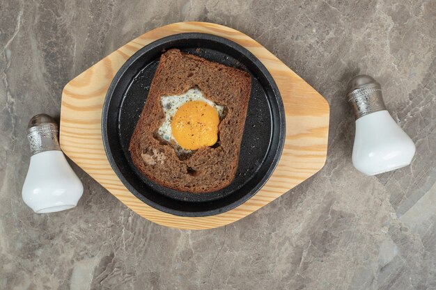 Spiegelei in Toastbrotscheibe auf schwarzem Teller. Hochwertiges Foto