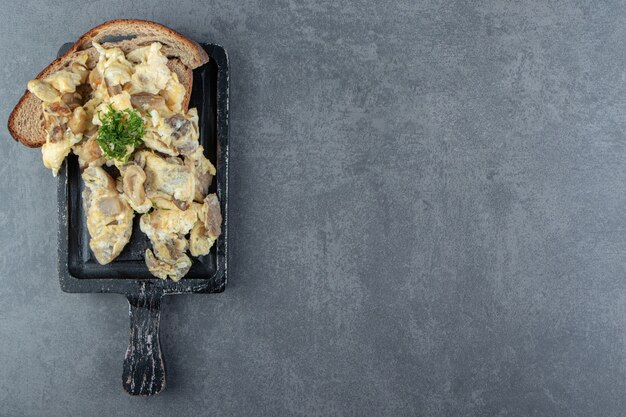 Spiegelei mit geschnittenem Fleisch auf schwarzem Brett.