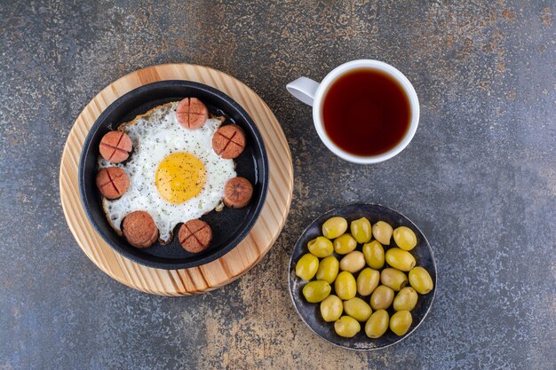 Spiegelei mit Würstchen, Oliven und einer Tasse Tee