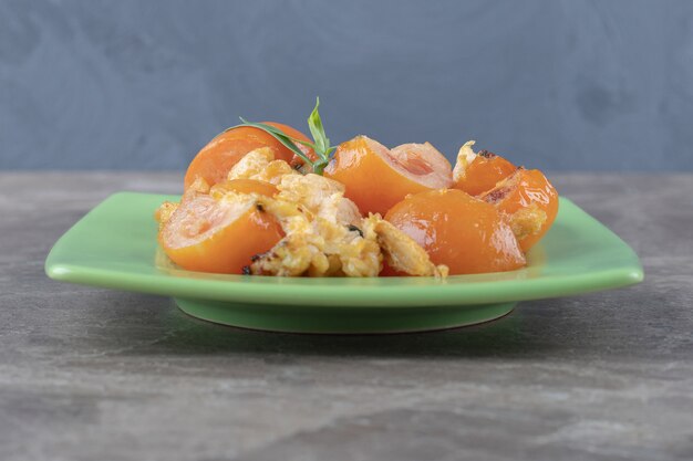 Spiegelei und Tomaten auf grüner Platte.