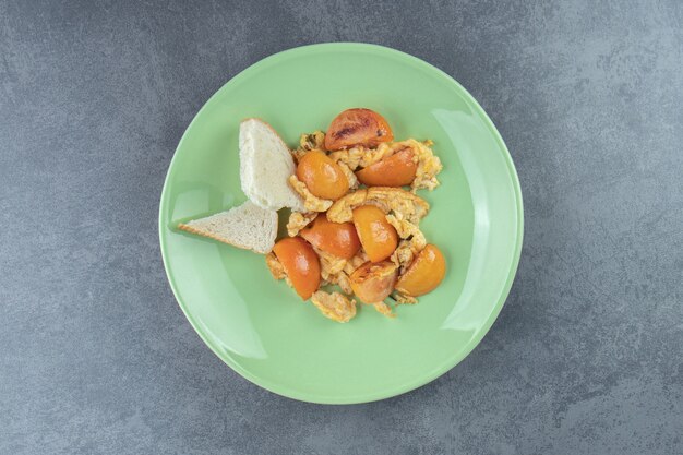 Spiegeleier mit geschnittenen Tomaten auf grünem Teller.