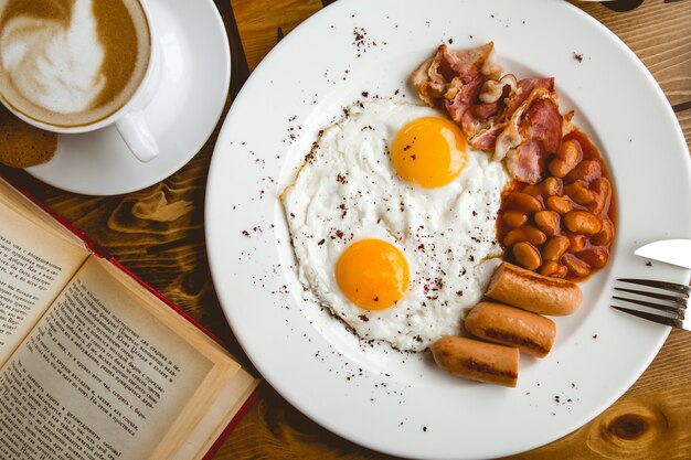 Spiegeleier mit Würstchen gebackenen Bohnen Speck Cappuccino Draufsicht