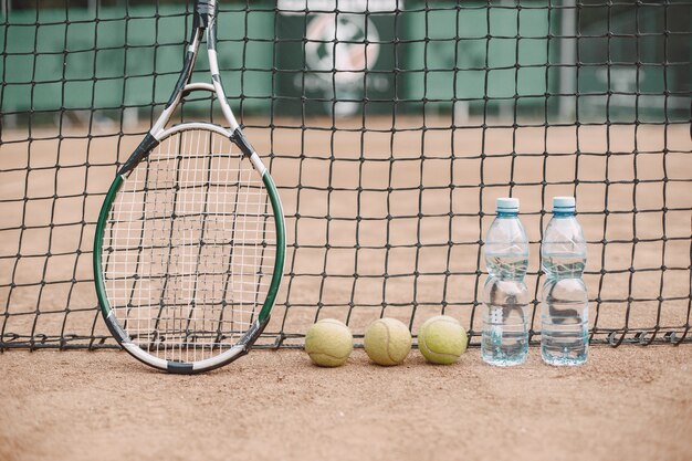 Spieler haben Tennisbälle, Schläger und zwei Flaschen Wasser auf dem Tennisplatz gelassen
