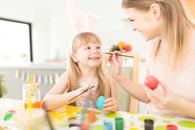 Spielerische Frau mit der Tochter, die für Ostern sich vorbereitet