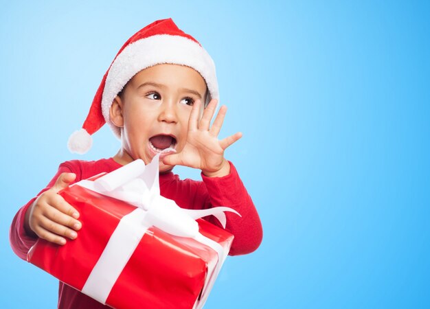 Spielerische Junge schrie, während ein Geschenk hält