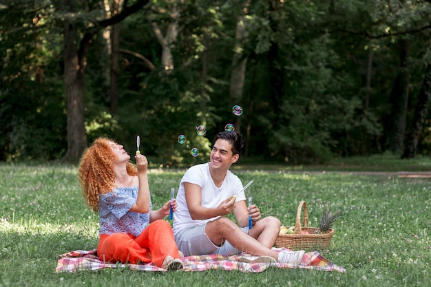 Spielerische Paare, die Blasen im Park machen