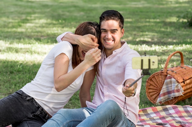 Spielerische Paare, die selfie im Park nehmen