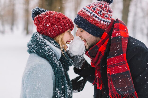 Spielerischer Mann und Frau, die Schnee isst