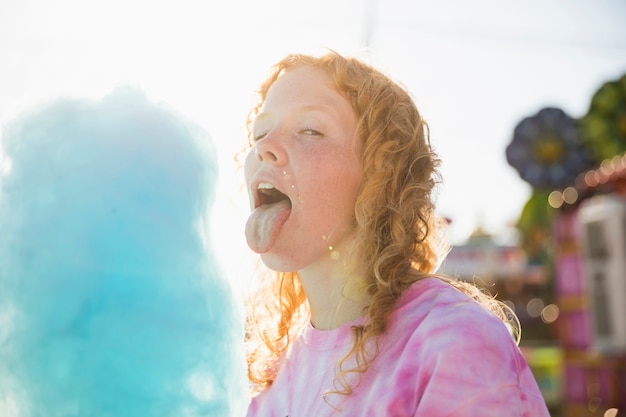 Spielerisches Mädchen, das Kamera mit Zuckerwatte betrachtet