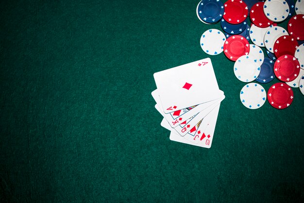 Spielkarte und Kasinochips des Royal Flush auf grünem Pokerhintergrund