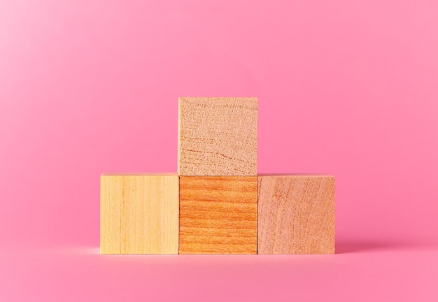 Spielzeug-holzwürfel mit kopienraum vor rosa hintergrund