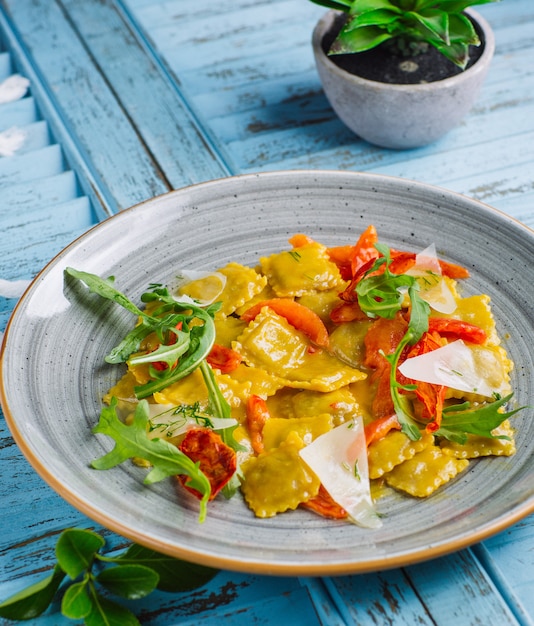 Spinat-Ricotto-Ravioli mit Parmesankäse, getrockneten Tomaten, Rucola