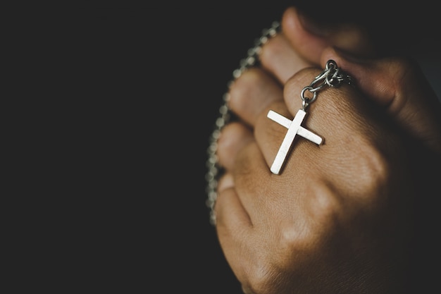 Spiritualität und Religion, Frauen in religiösen Konzepten Hände, die zu Gott beim Halten des Kreuzsymbols beten. Nun fing das Kreuz in seiner Hand auf.