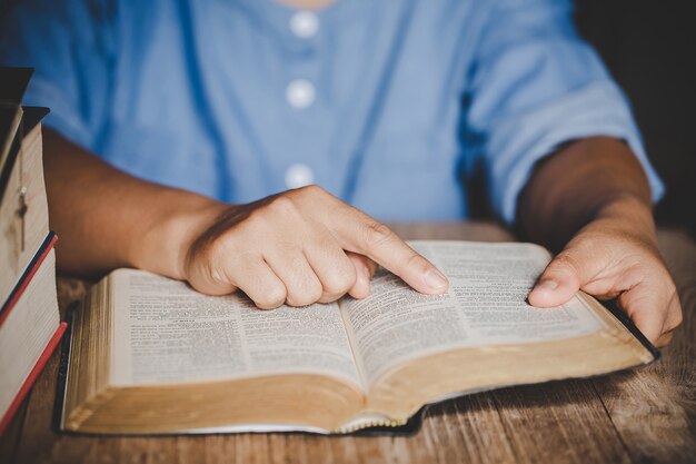 Spiritualität und Religion, Hände falteten sich im Gebet auf einer heiligen Bibel im Kirchenkonzept für Glauben.