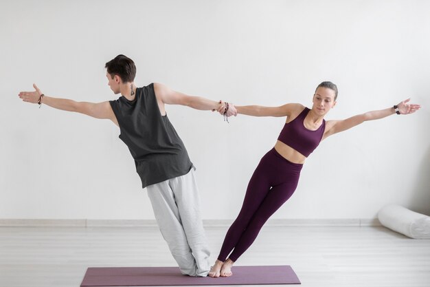 Spiritueller junger Mann und Frau, die zuhause Yoga praktizieren