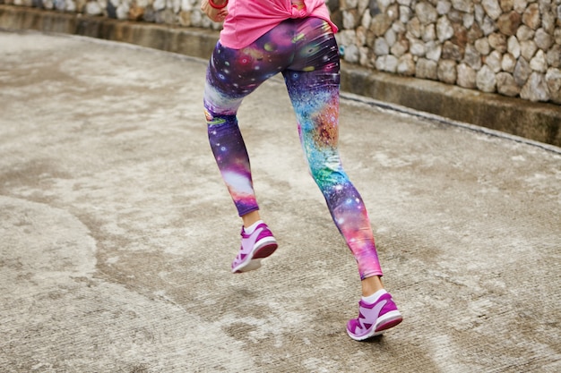 Sport, Finte und gesunder Lebensstil. Freeze Action Shot von fit Frau tragen stilvolle Leggings mit Raumdruck auf der Straße.