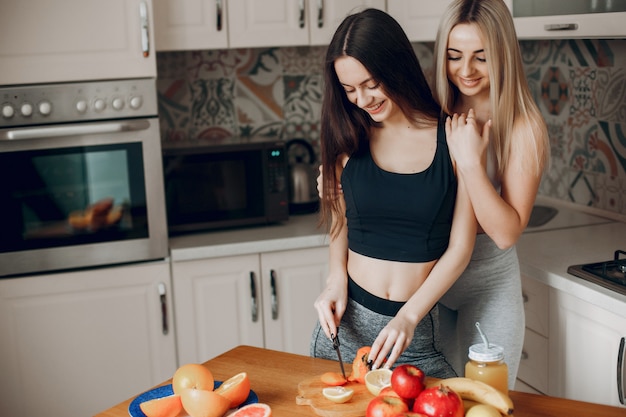 Sport girlss in einer Küche mit Früchten