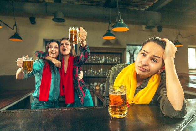 Sport, Menschen, Freizeit, Freundschaft, Unterhaltungskonzept - glückliche Fußballfans oder gute junge Freunde, die Bier trinken und den Sieg in der Bar oder im Pub feiern. Konzept der menschlichen positiven Emotionen