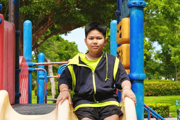 Sport- und Lifestyle-Konzept junger asiatischer Junge, der auf dem Spielplatz im Freien sitzt