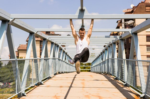 Sportiver junger Mann, der auf der Brücke trainiert