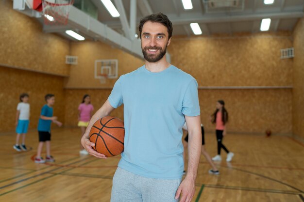 Sportlehrer mit mittlerem Schuss, der Ball hält