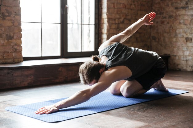 Sportler, der auf Übungsmatte nach dem Training im Fitnessstudio streckt