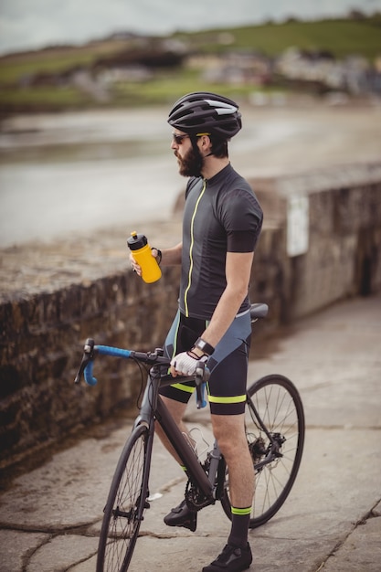 Sportler, der beim Fahrradfahren von der Flasche erfrischt