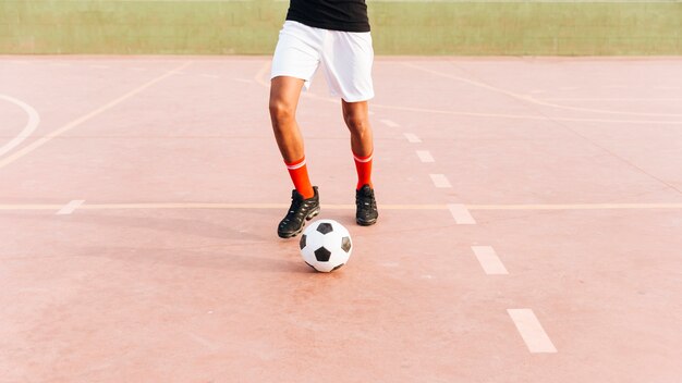 Sportler, der mit Fußball am Sportplatz spielt