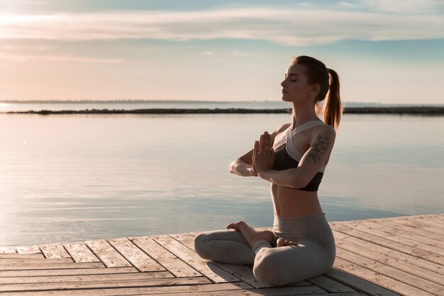 Sportlerinnen am Strand machen Meditationsübungen.