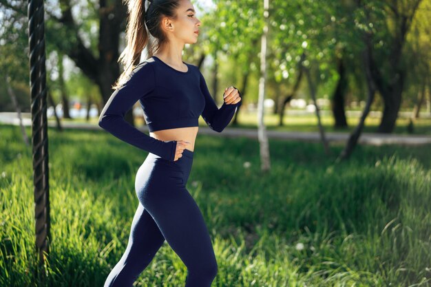 Sportlich fitte junge Frau, die früh morgens im Park joggt