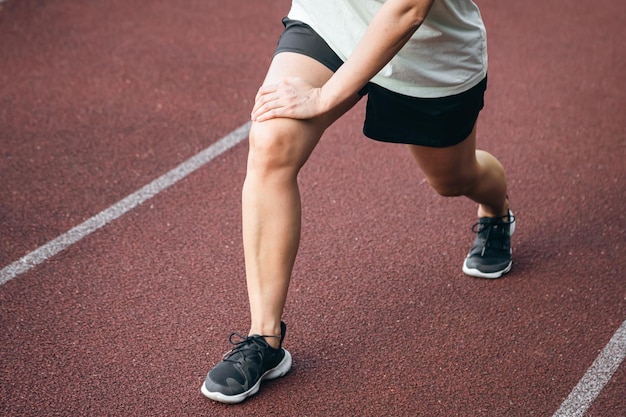 Kostenloses Foto sportliche dehnung und bewegung mit einer frau im freien auf einer strecke athletin frau im stadion für beine dehnung fitness und muskeln aufwärmen oder körper wellness