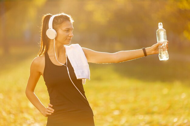 Sportliche Frau bietet eine Flasche Wasser